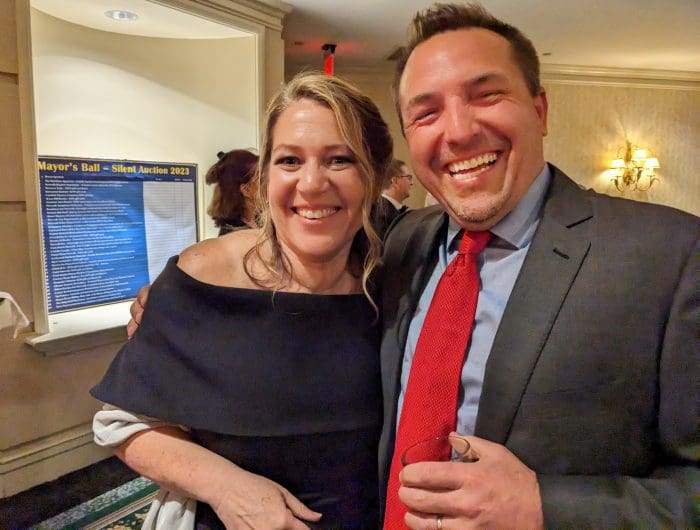 Shows Chief of Staff Laoise King with City antagonist Jason Milligan, at a social event.
