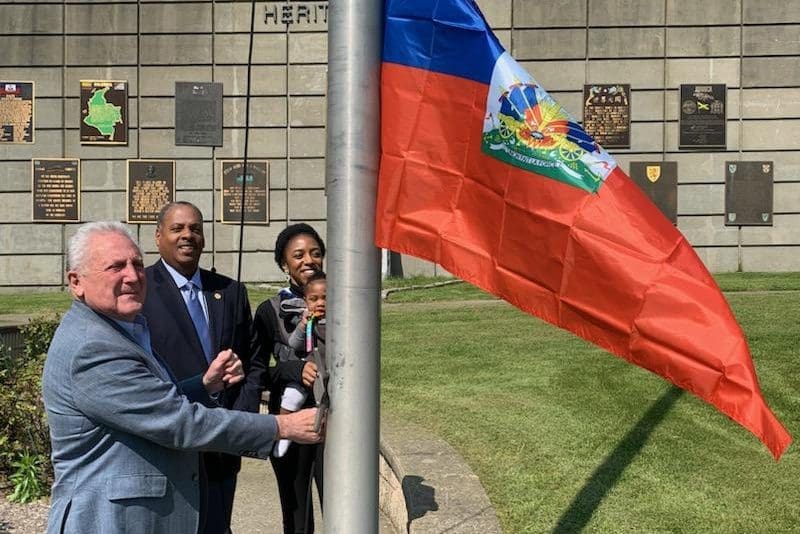 Norwalk's Mayor and Council President join a Haitian American Council member for a flag raising in a prominent location.
