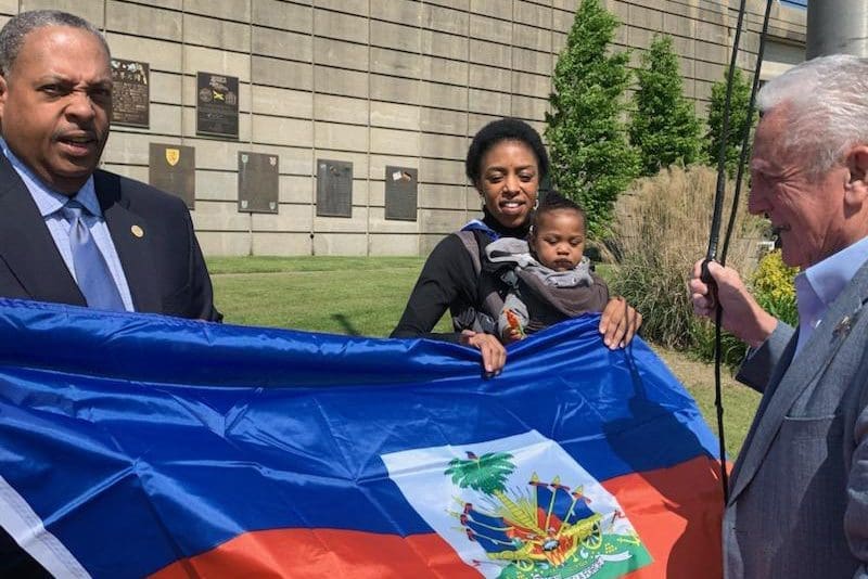 Haitian flag with four people, one a baby.