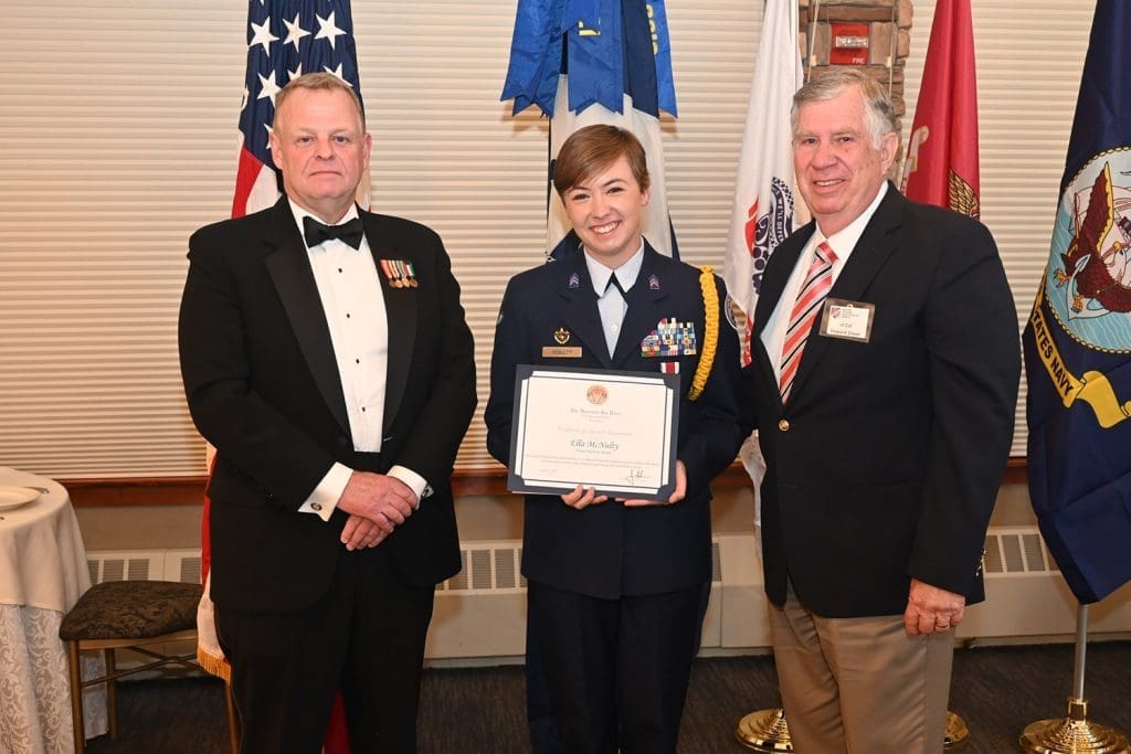 Senior military officers with a teen cadet and her award.